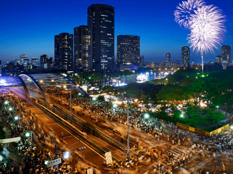 Photo des rues d’Osaka bondées pour le Tenjin matsuri avec un feu d’artifice — source Japan Travel